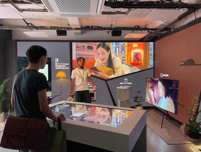 Screen TVs used for demonstrating product in a pop-up shop with two people in it