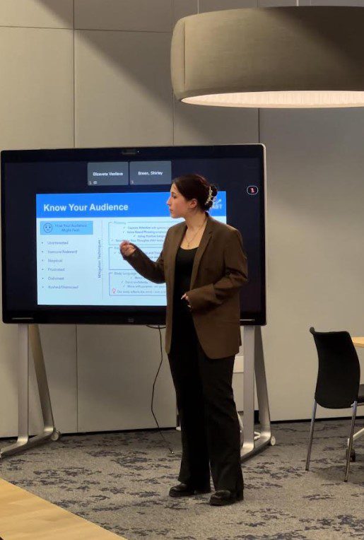 Elizaveta Vasileva giving a presentation in front of a screen for TMU Toastmasters