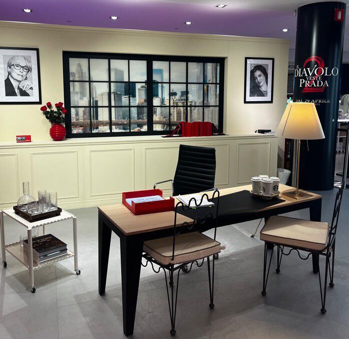 Modern office setup with a stylish desk and designer chairs. Black and white portraits adorn the cream walls