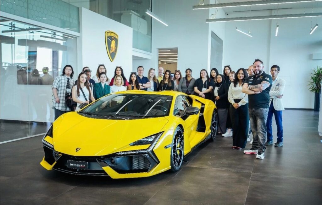 Students behind yellow Lamborghini car in showroom